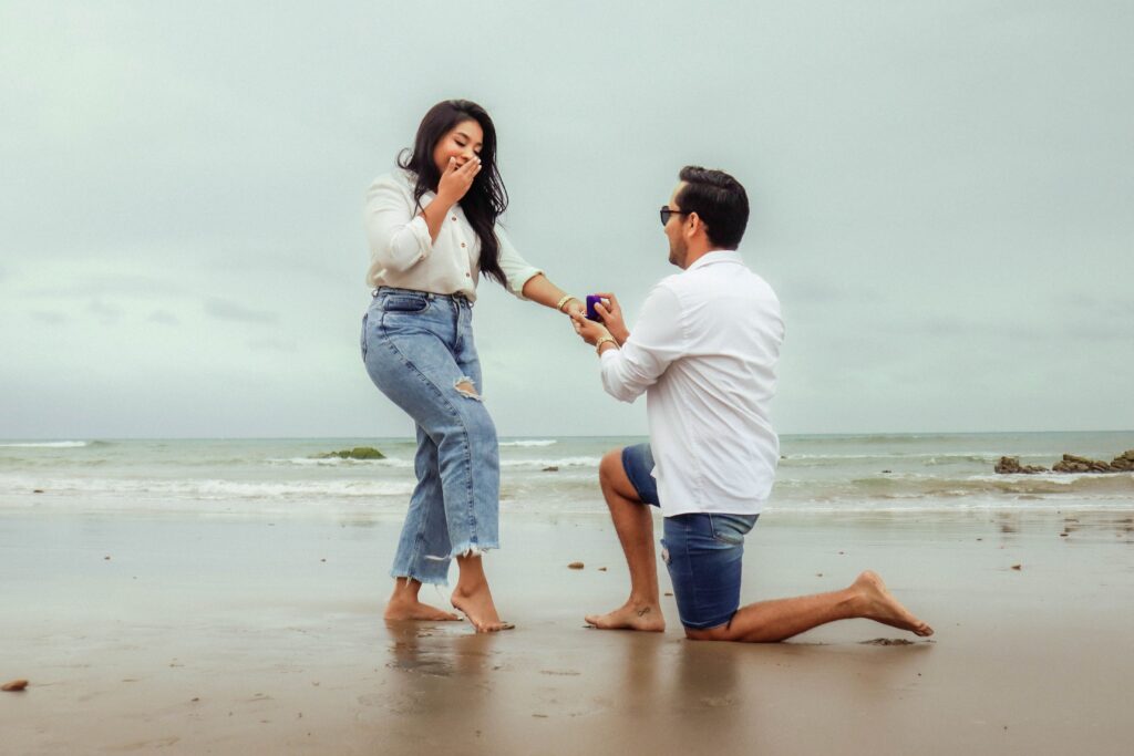 A man proposes to a woman on a scenic beach, capturing a lifelong memory.