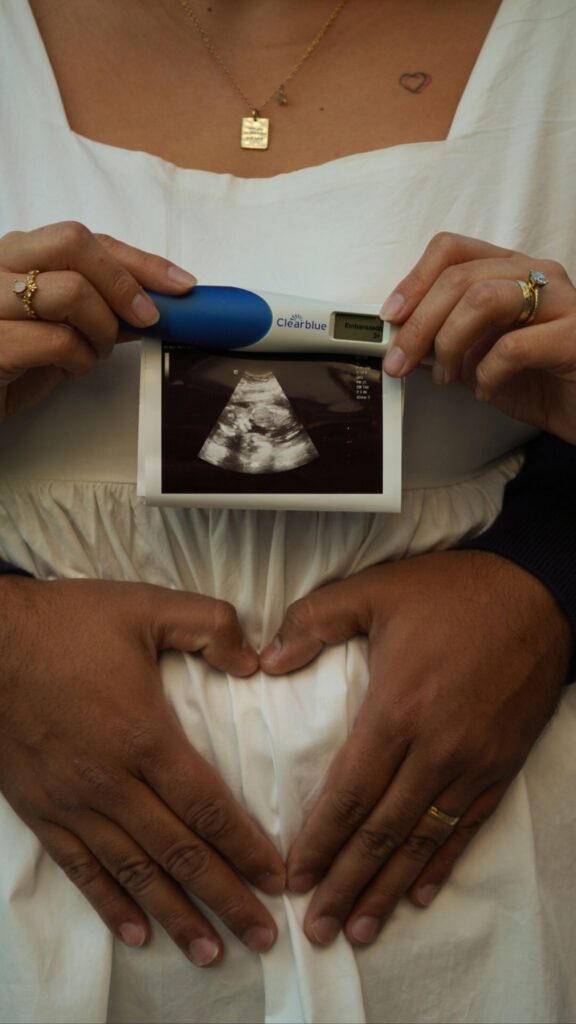 An expectant couple with ultrasound image and pregnancy test, showing their anticipation.