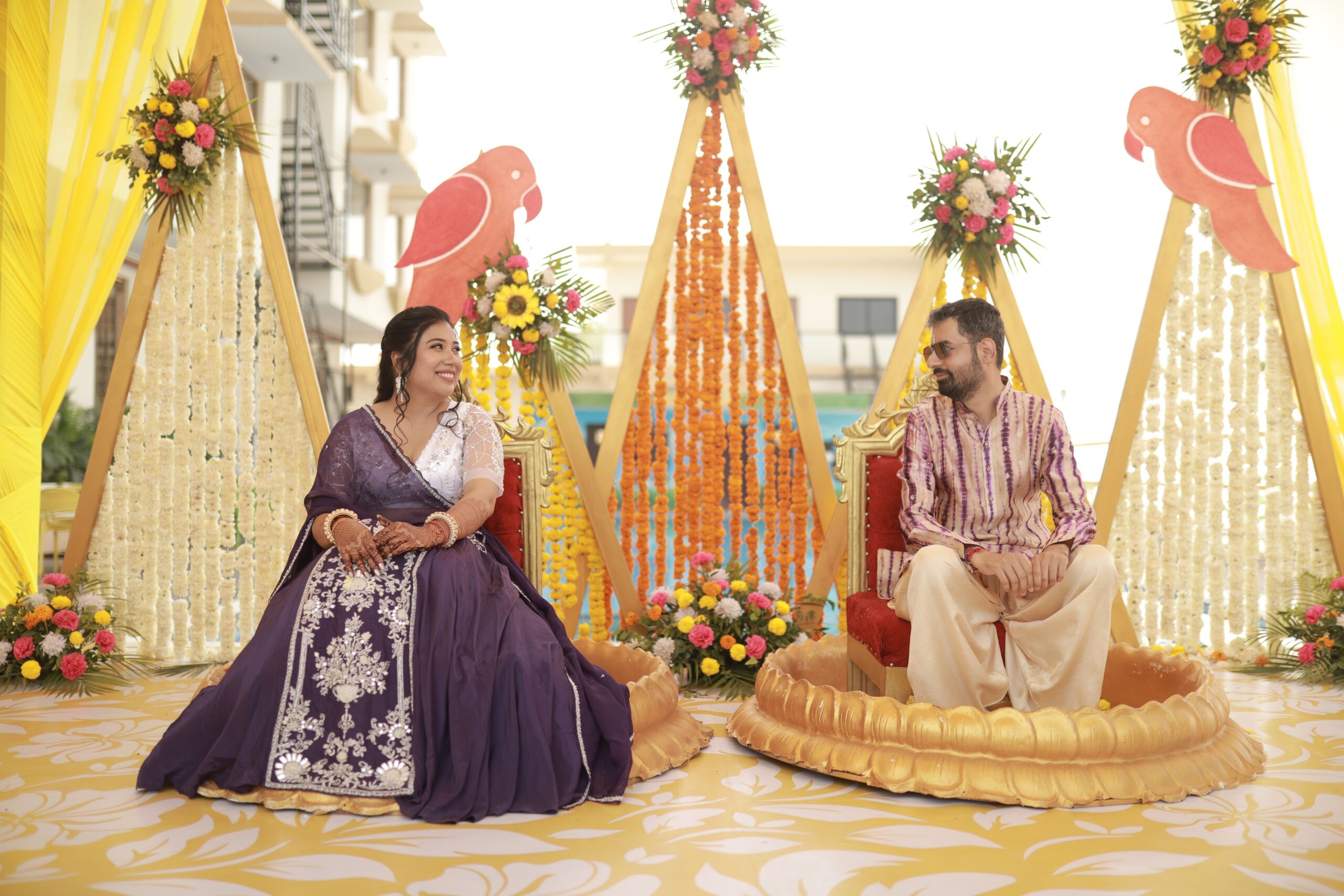 Bright and colorful traditional Indian wedding ceremony with smiling couple and floral decorations.