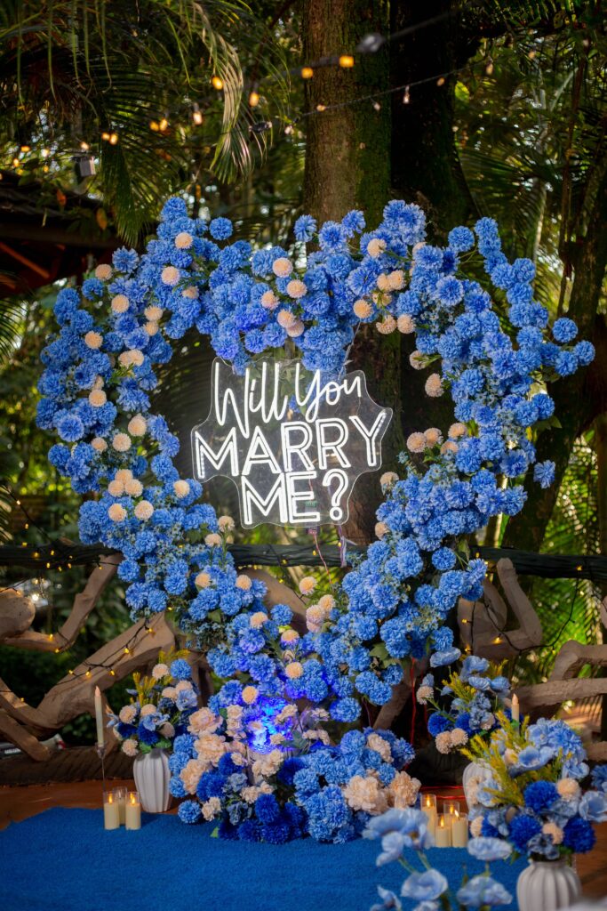 A heart-shaped floral arrangement with a neon 'Will You Marry Me?' sign, perfect for proposals.
