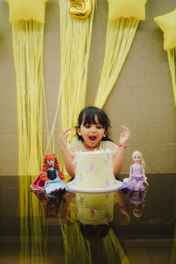 A joyful child celebrates her birthday with a cake and cheerful decorations.
