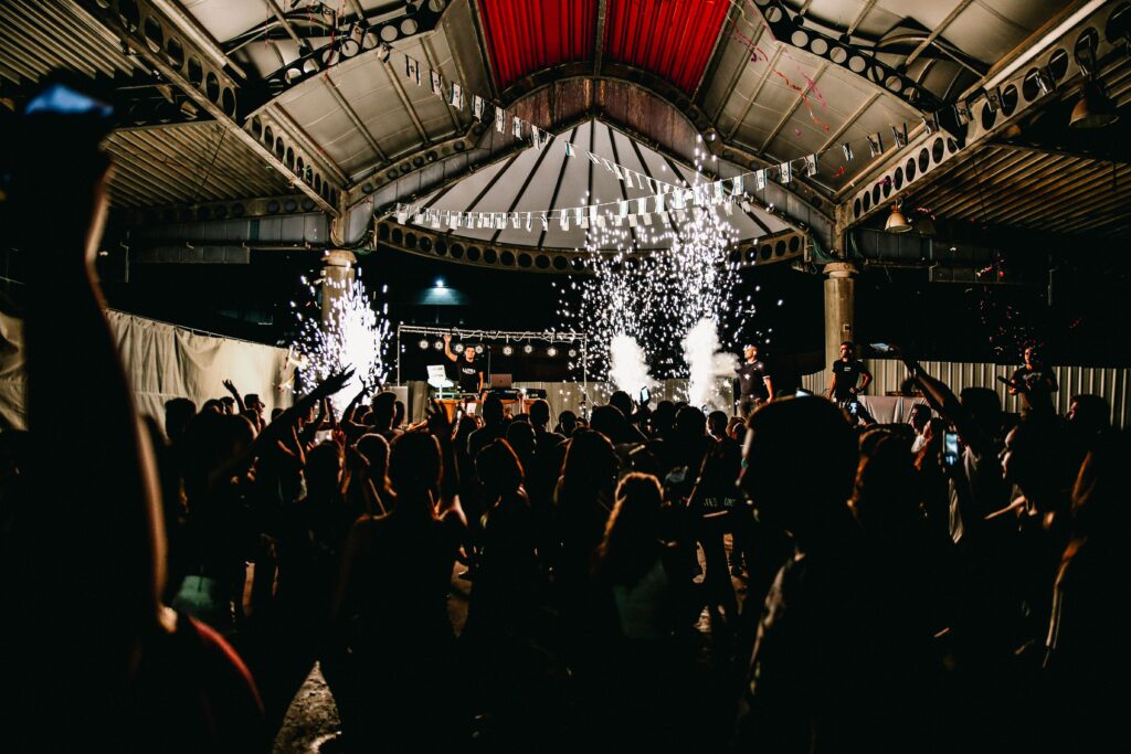 Lively nightclub scene with DJ, fireworks, and energetic crowd enjoying the night.